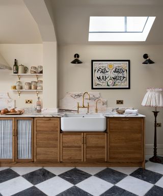 Devol wooden kitchen cabinets with a black and white checkerboard base and a pink marble countertop and backsplash