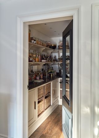 A pantry with dark countertops and a black door.