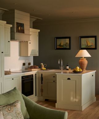 Small light green kitchen with a rattan table lamp and cozy coastal style