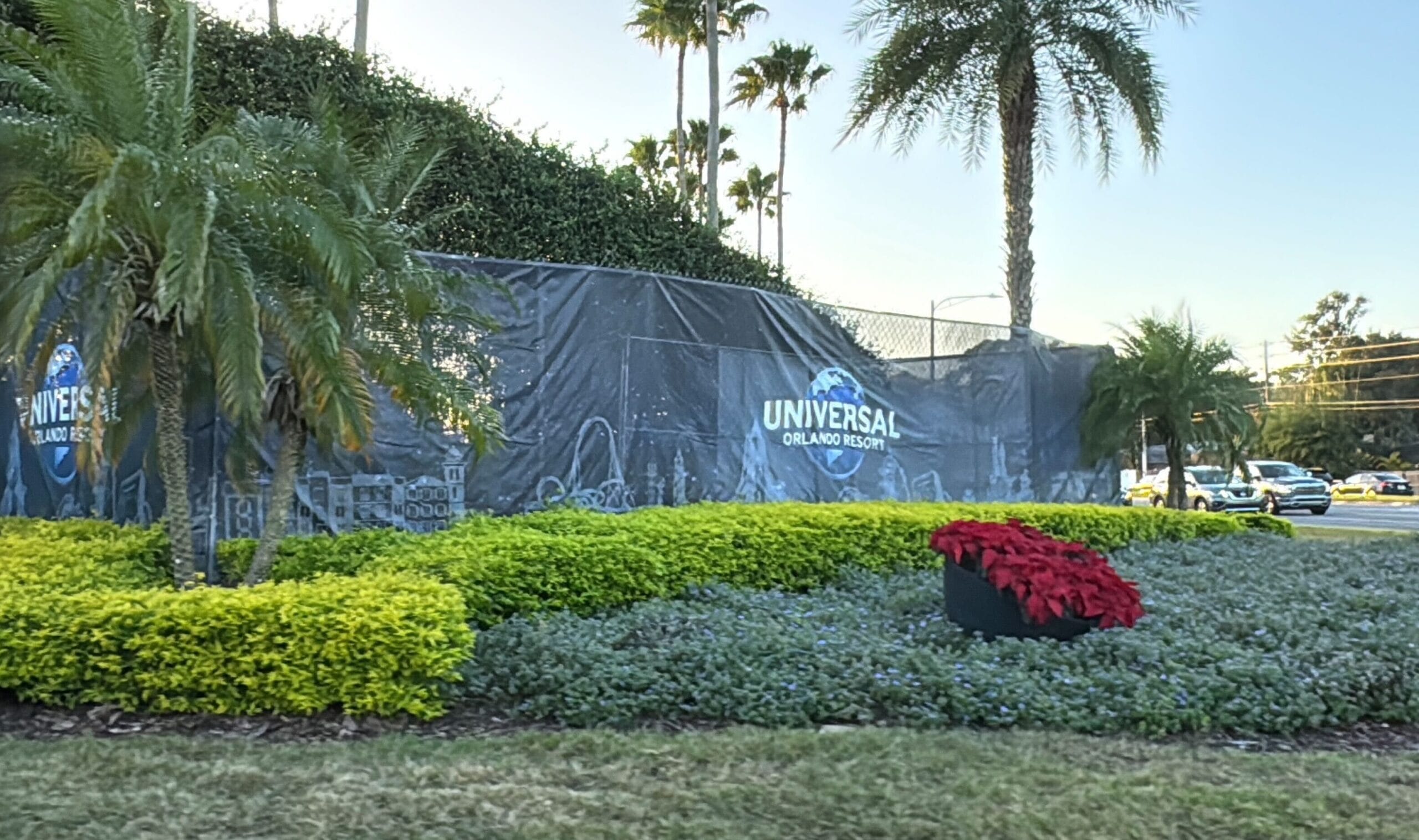 Universal Orlando Resort sign with tropical plants and flowers in the foreground.