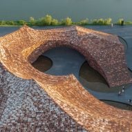 Kengo Kuma towers over the sculptural community center with a curved bamboo roof