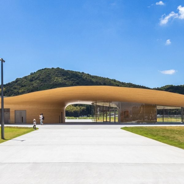 Kengo Kuma towers over the sculptural community center with a curved bamboo roof