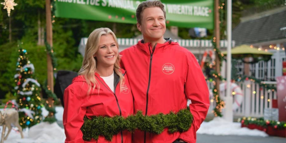 Two news anchors in red jackets outside