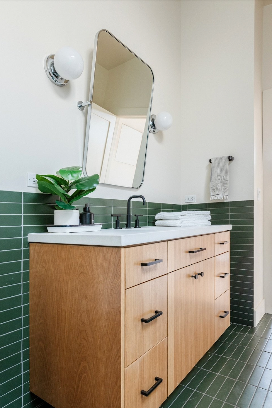 Modern bathroom vanity with sink mirror and green tiled walls