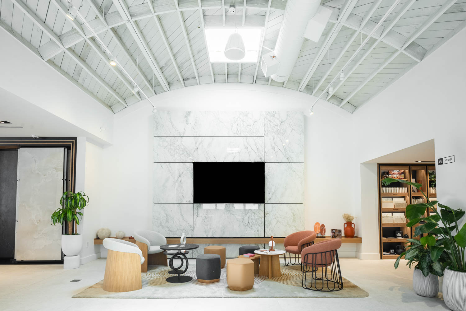 Showroom with high, rounded ceilings, seating area and marble base television