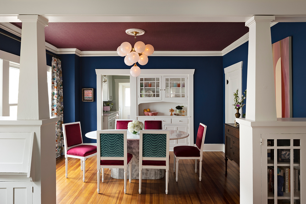 Dining area with a round table, stylish chairs and colorful walls