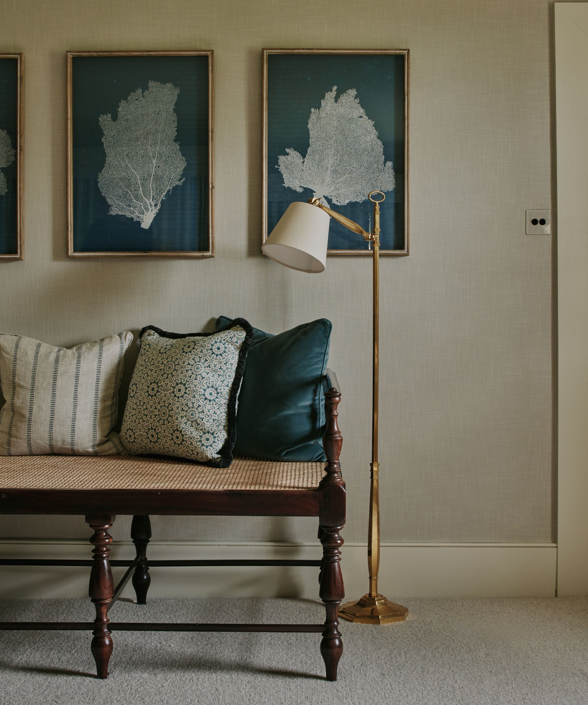 Tapete hallway with a vintage mahogany seat seat with patterned pillow, a brass floor lamp and a trio of sea motif walls