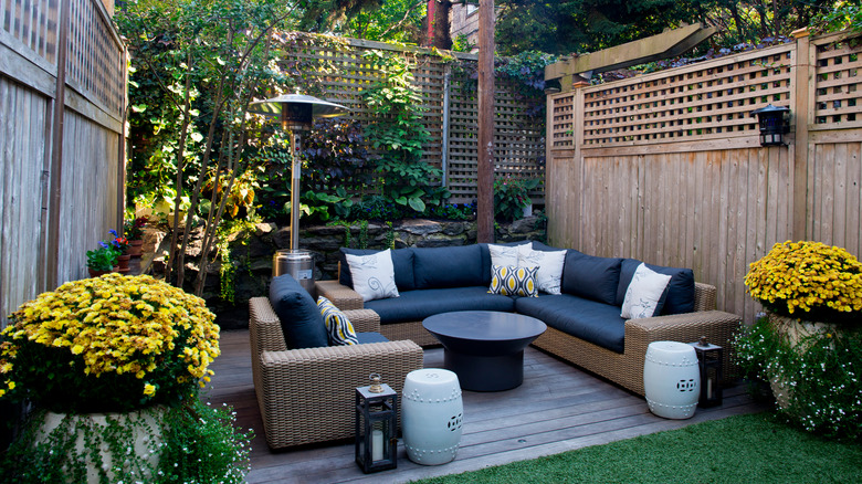 A walled backyard terrace is decorated with seating and accessories