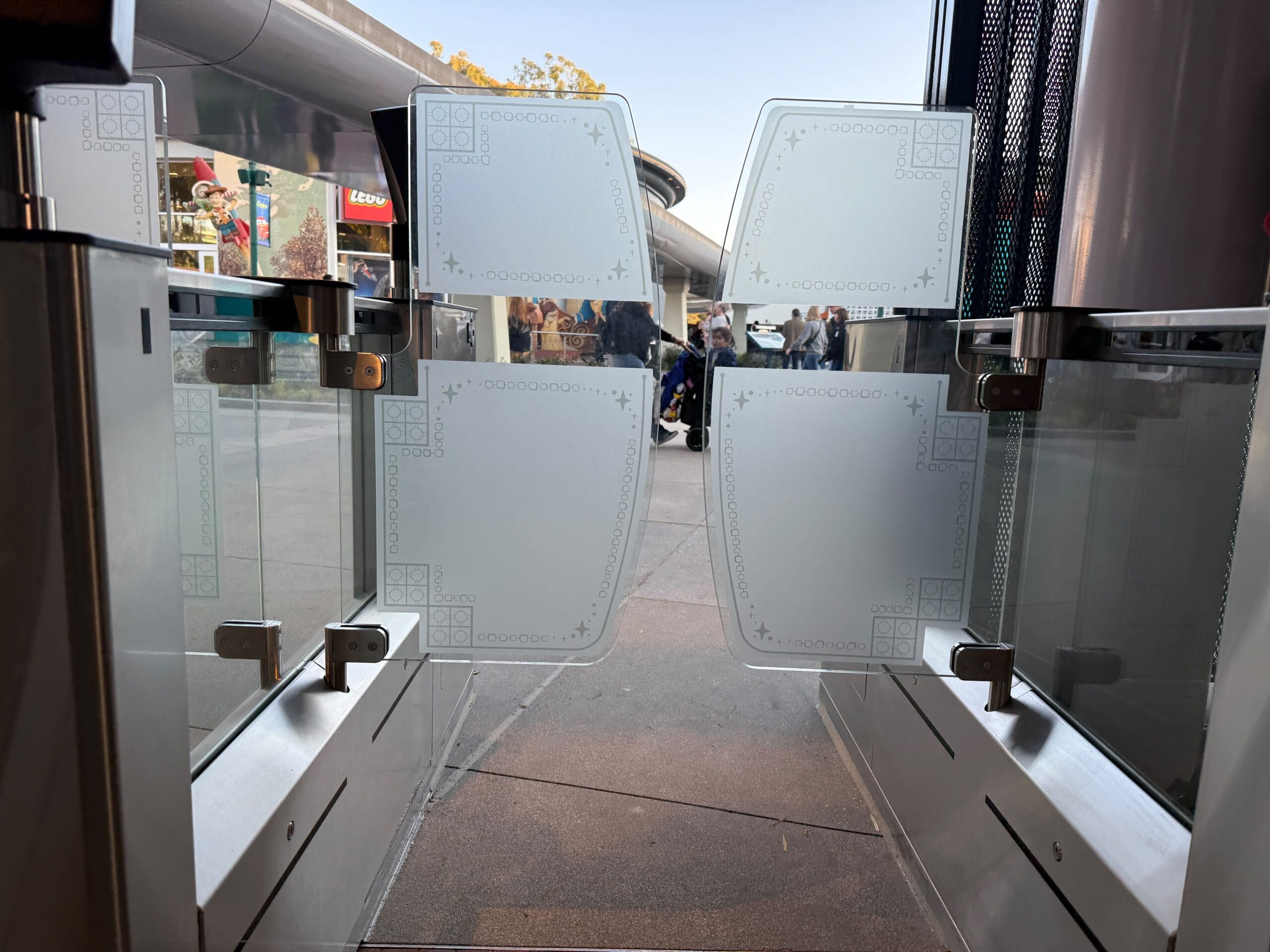 The frosted glass gates with decorative patterns slide and reveal a scene that lives with people and shops and reminds of the enchanting trips beyond the gates of the Disneyland Monorail.