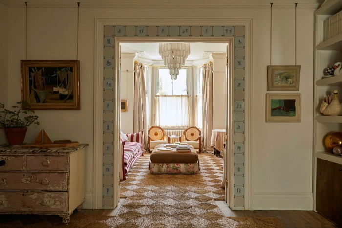 A look from one room to another through a wide door. The door is surrounded by a strip of white tiles with blue decorative figures. 