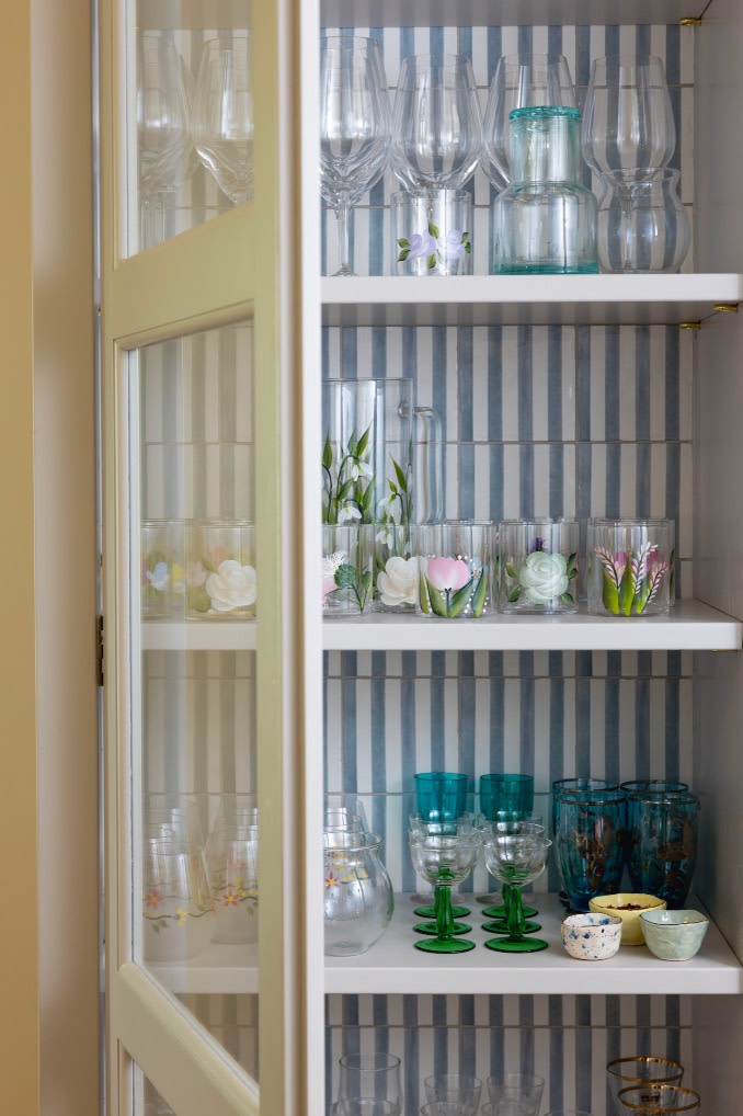 Blue and white striped tiles decorate the back of a glasses cabinet.