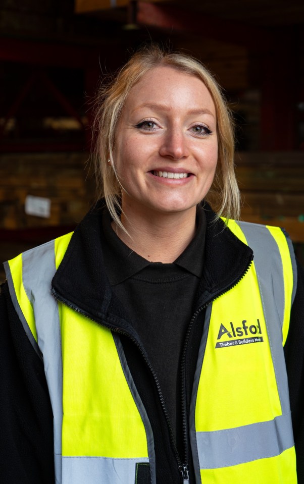 Portrait of a smiling woman who wears a yellow security vest with the Merchant logo of the Asfol wood and the builder.