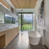 The primary en-suite has a soaked bathtub and showering that corresponds to a floor with a floor to the ceiling that creates an illusion of being outdoors. The wooden artificial lock reflects the essentials of the cupboards in the kitchen.
