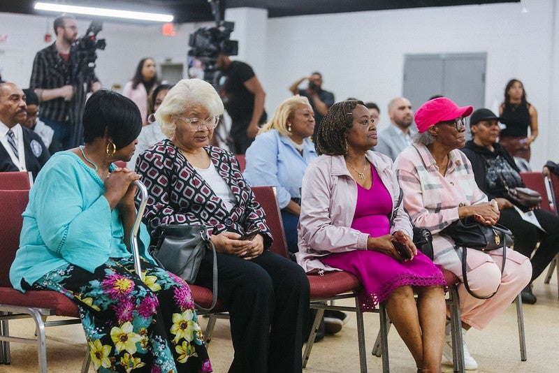 Several rows of sitting, mainly African -American women who take part in a community meeting.