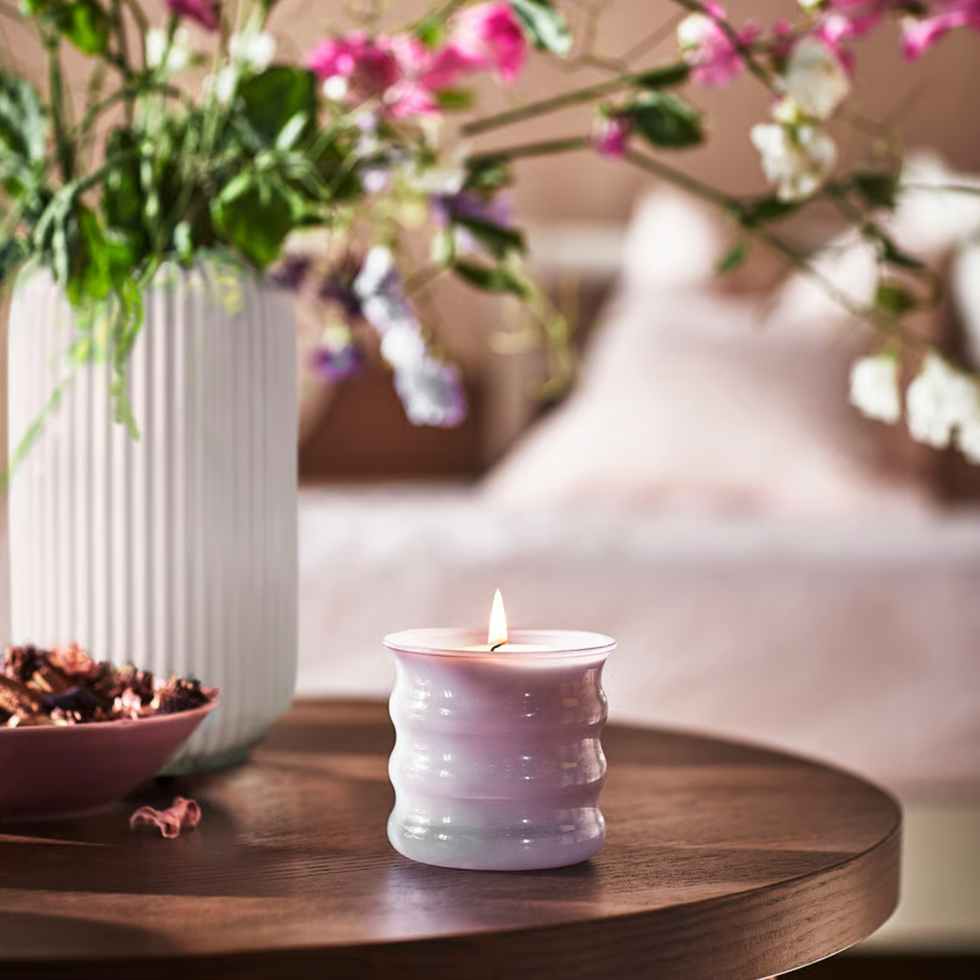A candle and a decorative bowl on a wooden table accompanied by a flower vase A candle and a decorative bowl on a wooden table accompanied by a flower vase