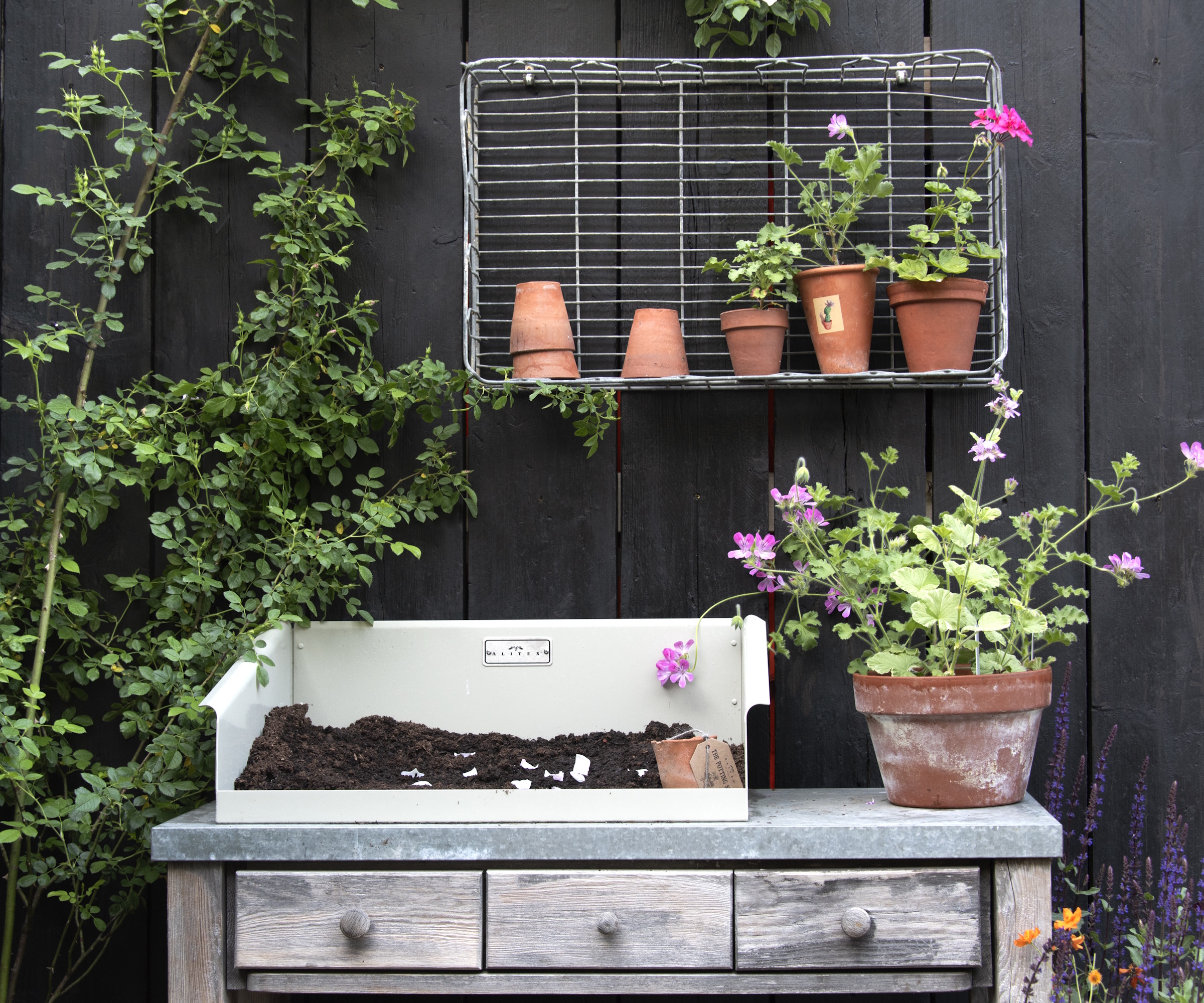 Casing bench in front of a black wooden background with terracotta pots