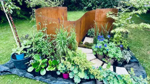 Claudia Sermbezis/BBC of the newborn garden designed by Jane Eastwood. The design includes a partition, several white bricks and various plants and flowers that deal with the design.