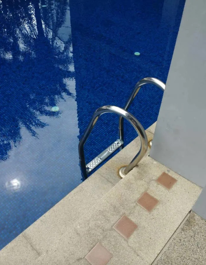 Powder ladder that rises in quiet water next to a tiled pool deck