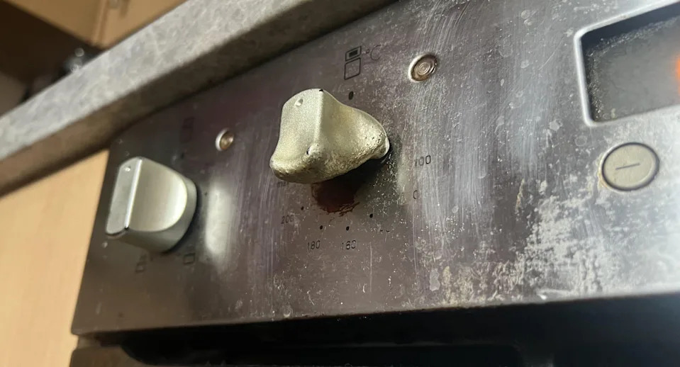 Close up of an oven control panel with visible wear, which shows three buttons