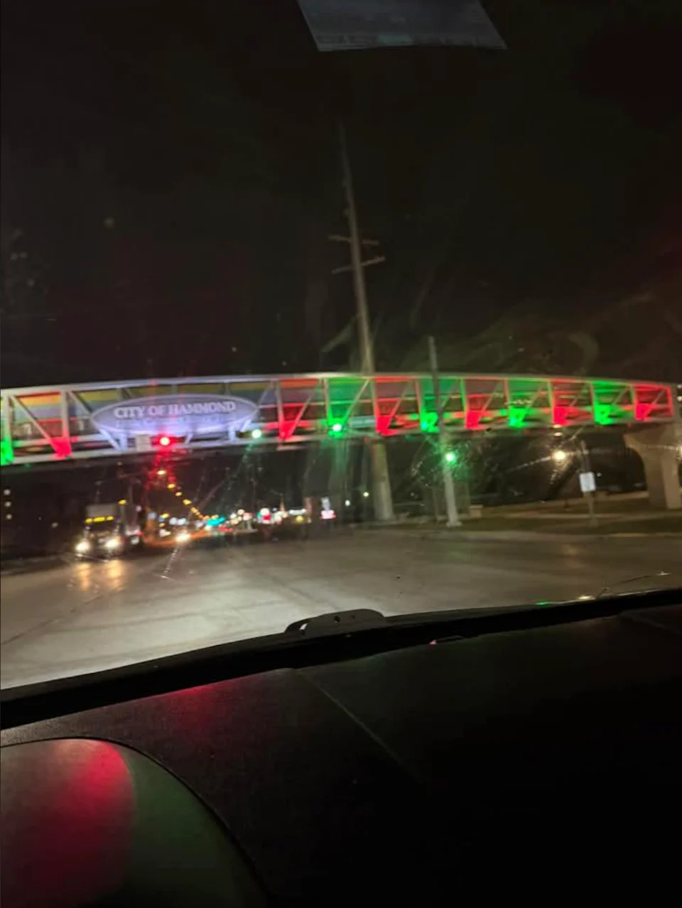 Night look on an illuminated pedestrian bridge over a street with "City of Hammond" Shield and traffic lights visible
