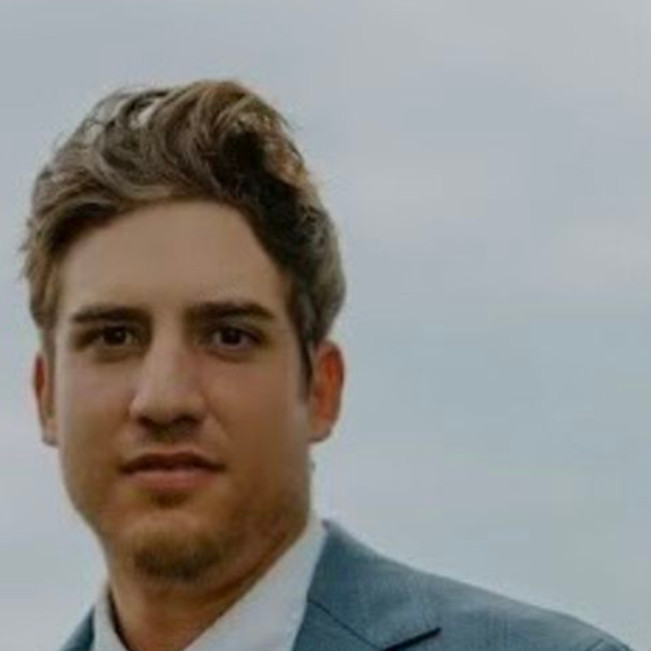 A headshot photo of garden expert Michael Clark: A man in a gray suit jacket with brown hair that looks into the camera