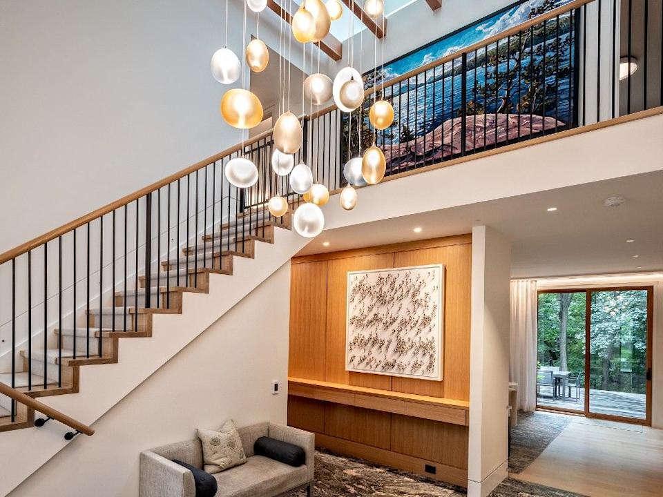 The architects opened the front hall to the roof and added a skylight and exposed rafters. Muscoca granite tiles and a hanging light sculpture of glass kisses improve the upscale rustic look.