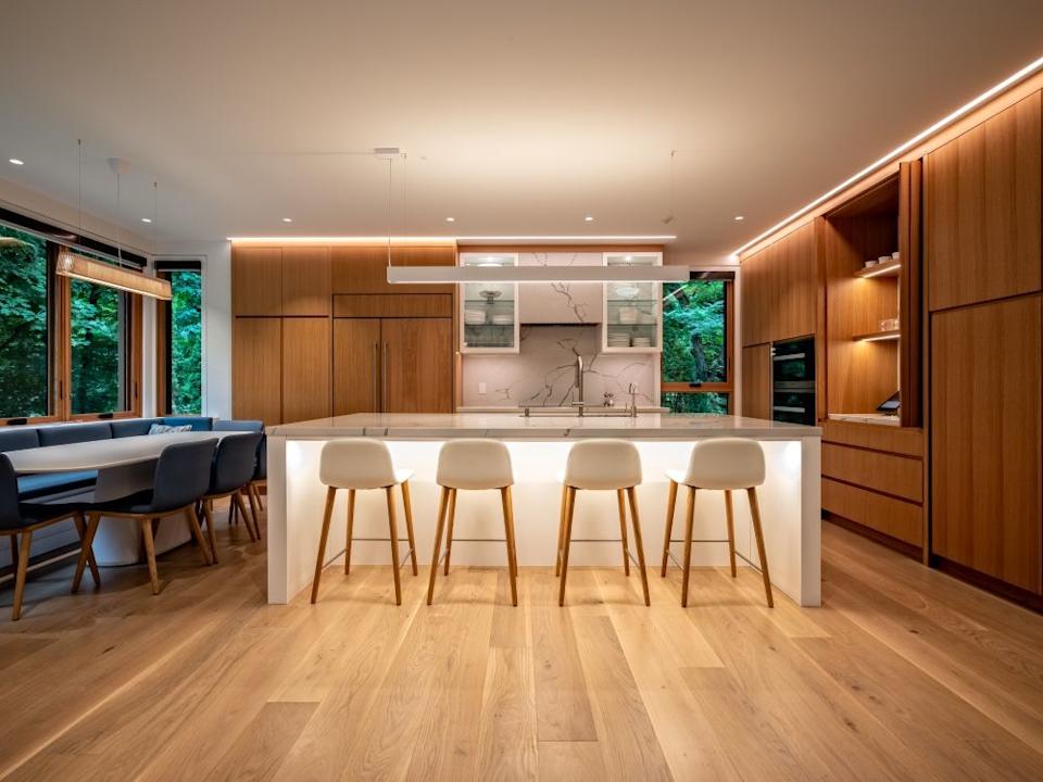 The kitchen has honey -colored white oak cabinets, a shiny quartz counter and a back splash as well as a leaf face. Due to the bump-out in the breakfast area, the owners feel like under the trees.