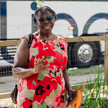 A black woman in a colorful dress made of res, beige, white and black patterns. 