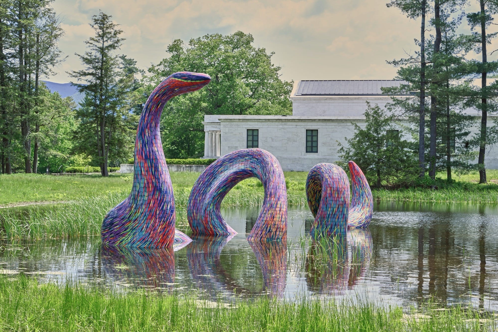 A sculpture of a colorful snake by Javier Senosiain in a pond