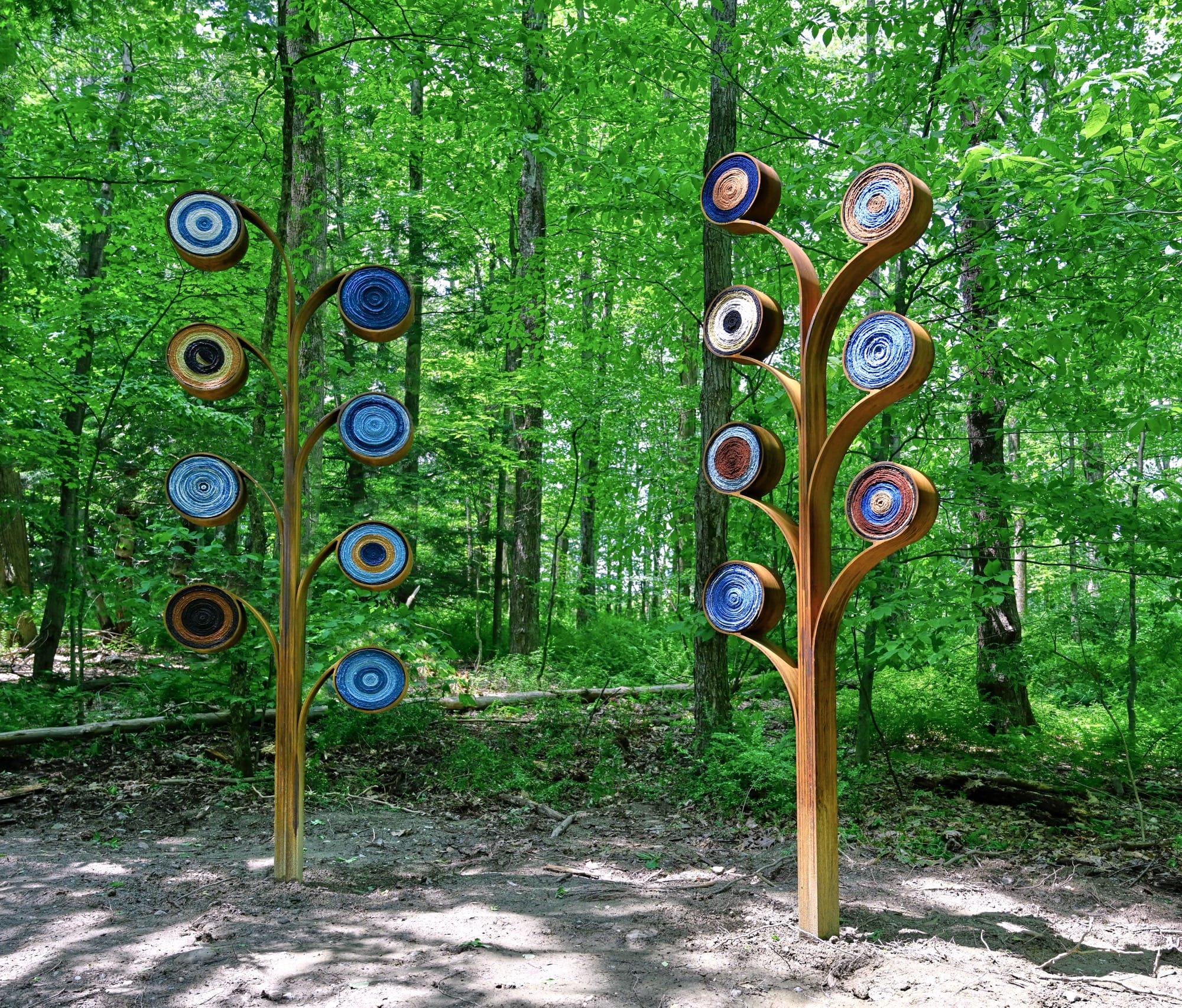 Two abstract tree forms that are installed in a forested area of artists Aboubakar Fofana with colored fiber elements