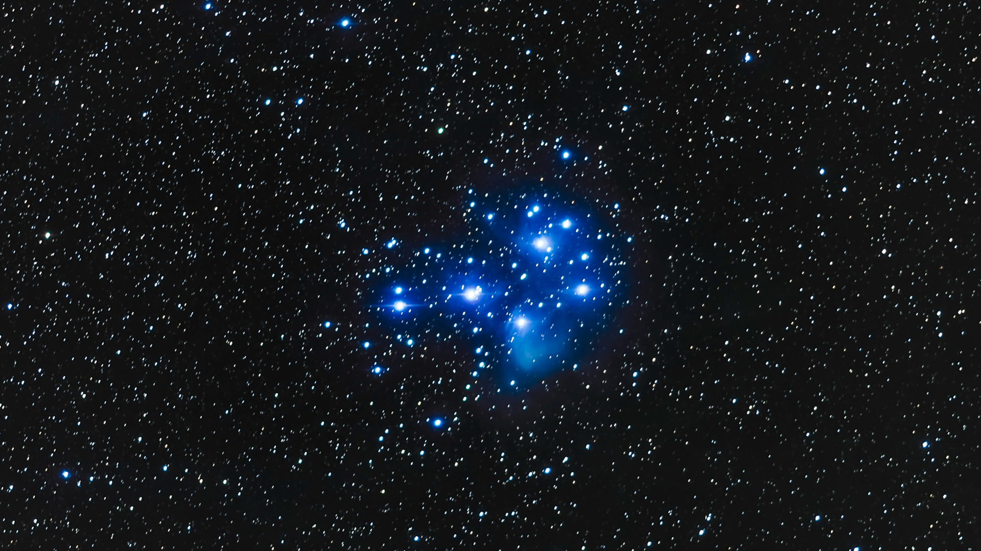 A collection of light blue, bright blue stars is shown in the middle of a picture that hangs on a dense star of the stars with lower performance, which are framed by the blackness of space.