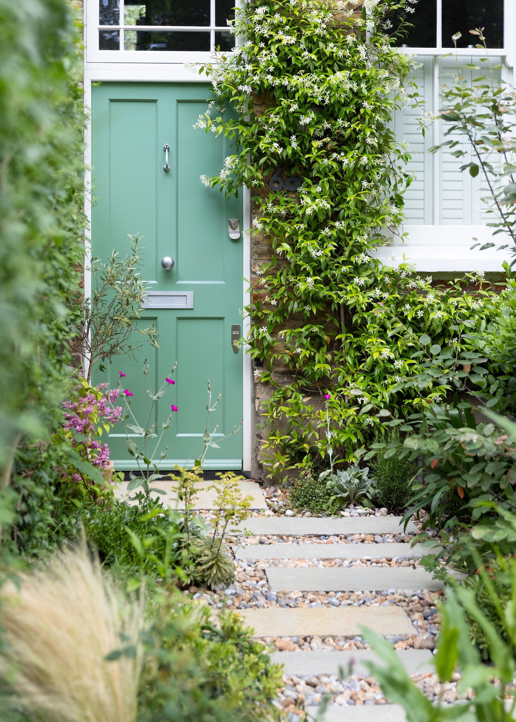 Green entrance door with garden path made of staggered slabs and large gravel