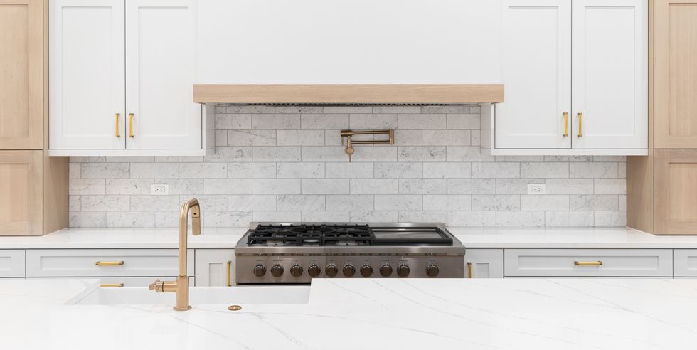 a kitchen detail with white and white oak cabinets and a gold faucet.
