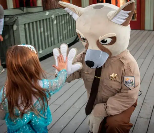 Fox mascot gives high-five to a young girl in princess outfit